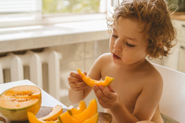 Cute beautiful little boy eating fresh melon