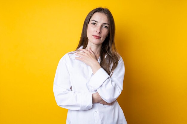 Cute beautiful young woman in a white shirt on a yellow background