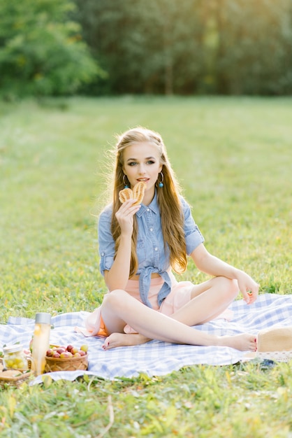 Cute beautiful young and youthful girl with professional makeup sitting on plaid, summer picnic. 