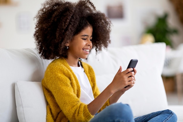 최신 모바일 앱을 즐기는 귀여운 흑인 소녀