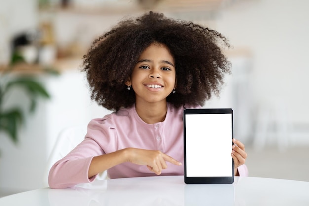 Photo cute black girl schooler showing digital tablet mockup