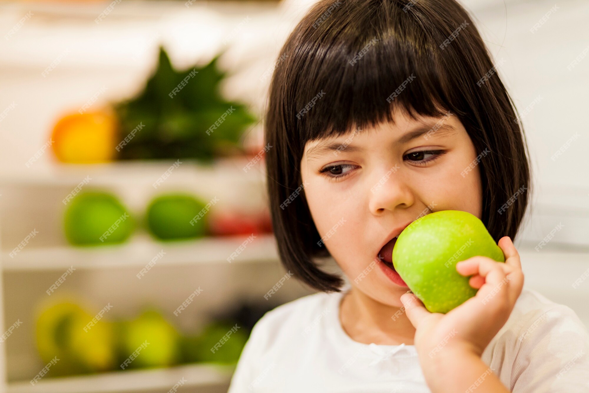 Premium Photo | Cute black hair little girl eating green apple Premium Photo | Cute black hair little girl eating green apple