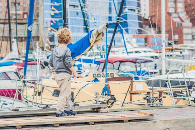 Cute blond boy looking at yachts and sailboats.