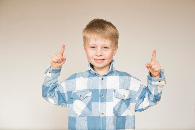 Un ragazzo biondo carino mostra la direzione con il dito.