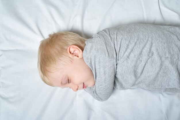 Cute blond boy sleeping with his hand under his head. 