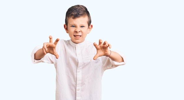Cute blond kid wearing elegant shirt smiling funny doing claw gesture as cat aggressive and sexy expression