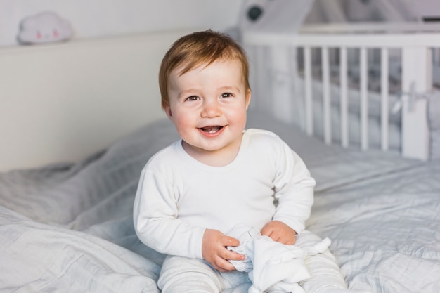 Photo cute blonde baby in white bed