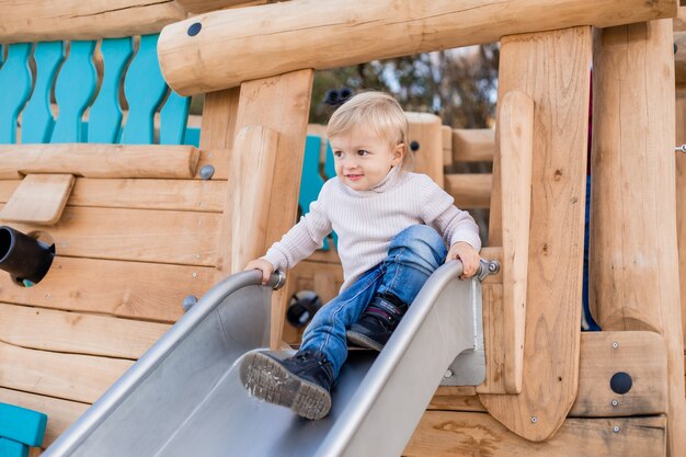 cute blonde boy playing on a wooden sports playground outdoors