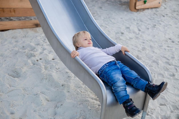 cute blonde boy playing on a wooden sports playground outdoors