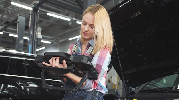 Cute blonde car mechanic working in a car service