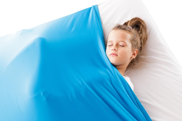 Cute blonde caucasian girl sleeping on a mattress under a blue cozy blanket