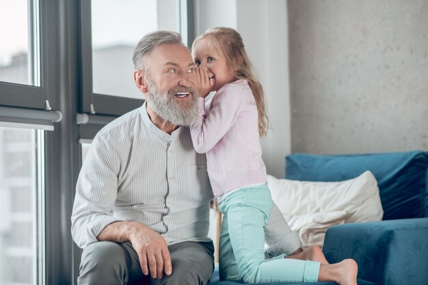 A cute blonde girl sharing secrets with her father