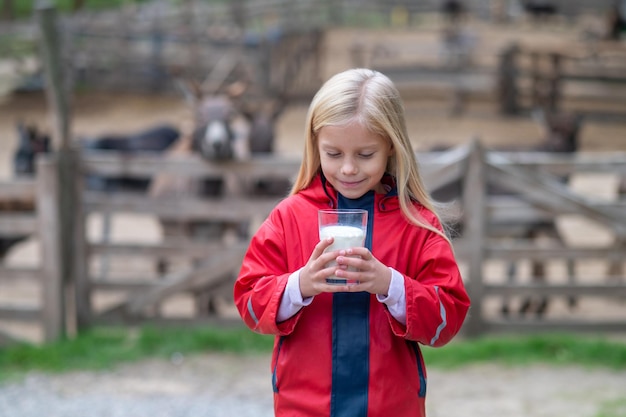 A cute blonde long-haired girl holding a glass with milk