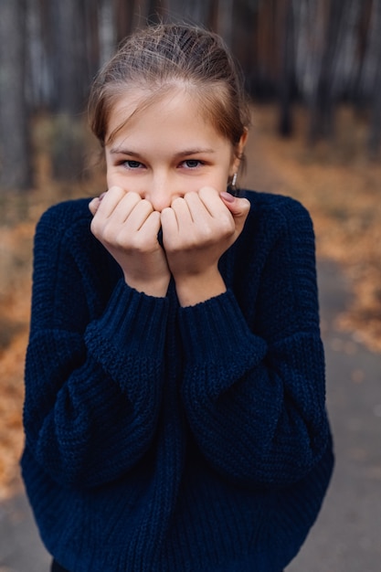 Foto adolescente biondo sveglio nel parco di autunno. ragazza che sta sulla foresta