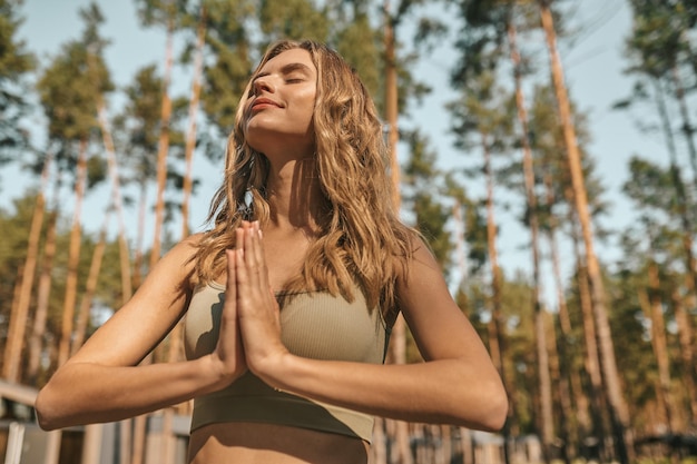 Foto donna bionda sveglia che pratica yoga fuori e sembra rilassata