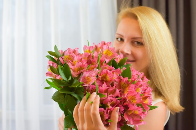 女の子のための新鮮な花の花束の美しい花束を持つかわいいブロンドの女性