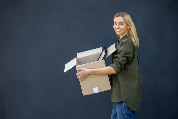 cute blonde young woman carrying boxes in hands