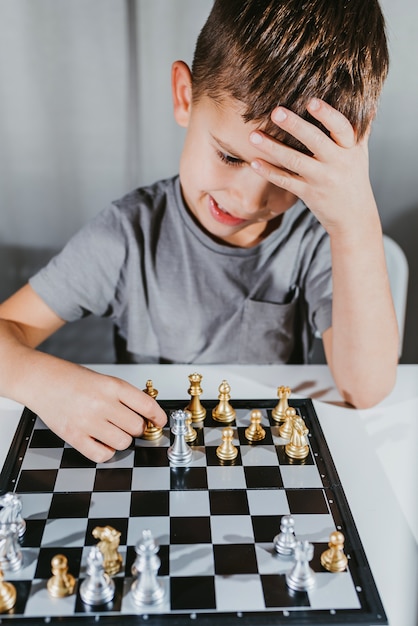 Cute boy 5 years old plays chess by himself in his room at home