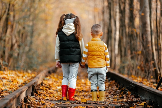 写真 秋のロマンチックな場所で秋の時間を愛のトンネルを笑顔の鉄道の上を歩くかわいい男の子と女の子