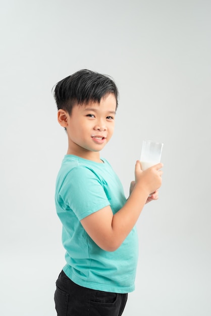 Cute boy in blue shirt holding glass of milk on white background