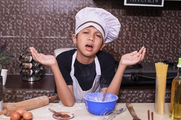 Cute boy in chef uniform showing dissapointed feeling with hand gesturing failed in the kitchen