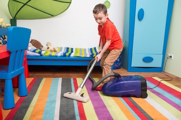 Cute boy cleaning floor with hoover the boy is cleaning up his room