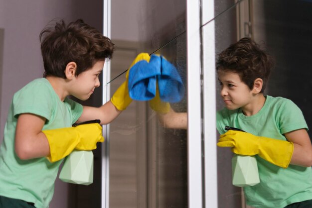 스프레이를 사용하여 거울을 청소하는 귀여운 소년