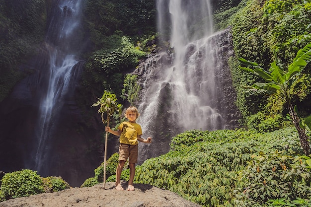 Cute boy depicts the king of the jungle against the backdrop of\
a waterfall childhood without gadgets concept traveling with\
children concept childhood outdoors concept