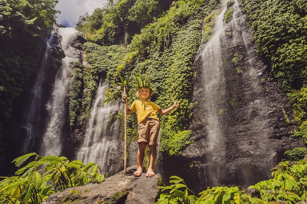 Cute boy depicts the king of the jungle against the backdrop of\
a waterfall childhood without gadgets concept traveling with\
children concept childhood outdoors concept