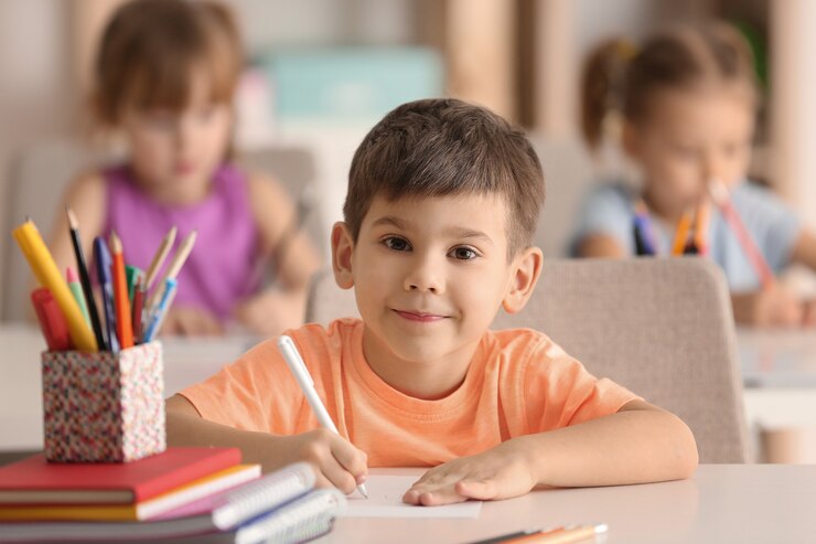Photo cute boy drawing in classroom