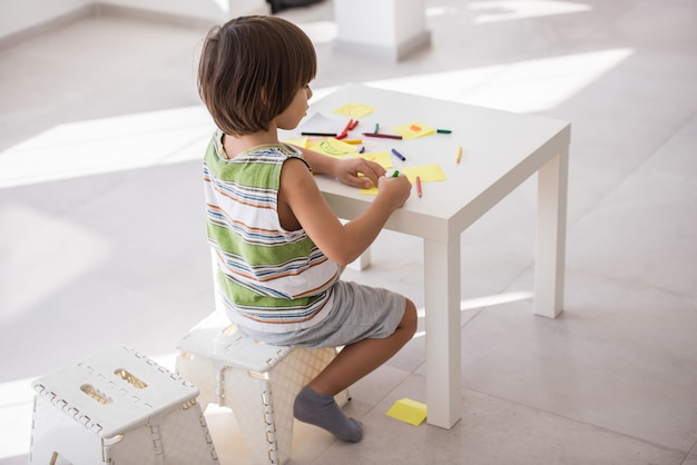 Cute boy drawing at home