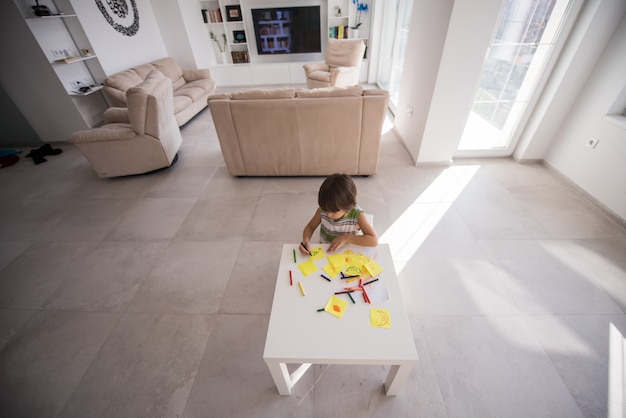 Cute boy drawing at home