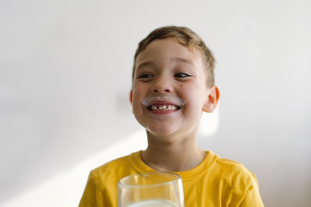 Cute boy drinks kefir or milk funny portrait of a boy with a milk mustache