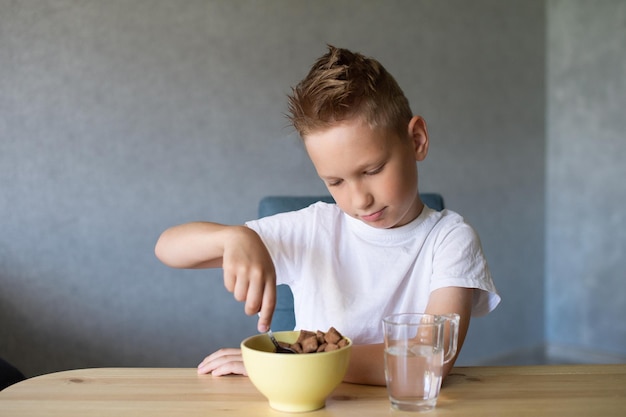 Cute boy eats a dry breakfast at home and smiles