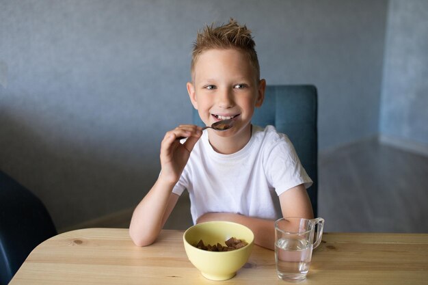 Cute boy eats a dry breakfast at home and smiles