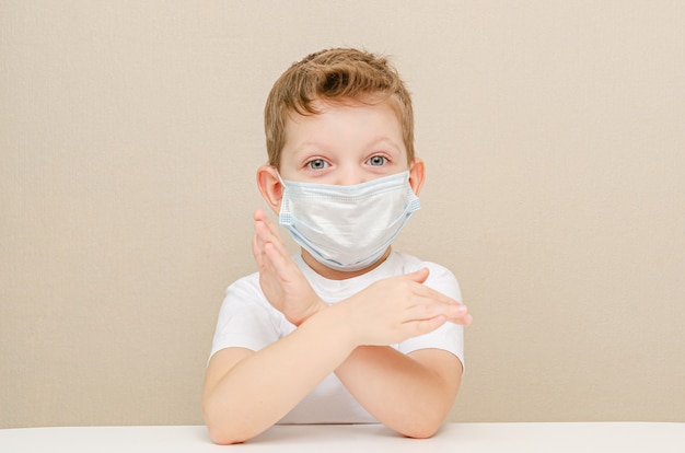 Cute boy of four years in a medical mask. Quarantined children due to an epidemic. The boy forbids. Gesture - hands are skrenny.