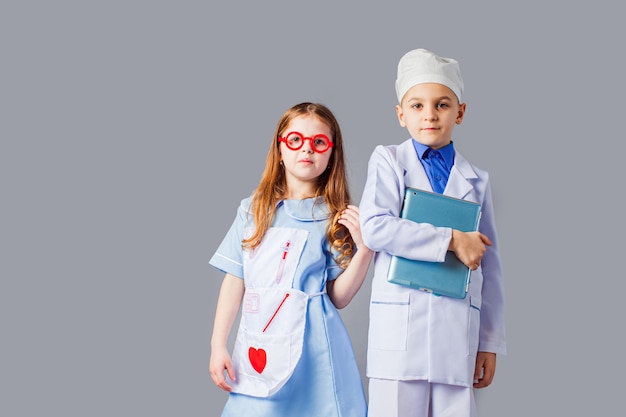 Милый мальчик и девочка в медицинской форме играют как врачи