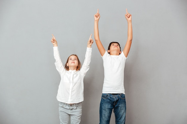 Cute boy and girl standing and pointing up