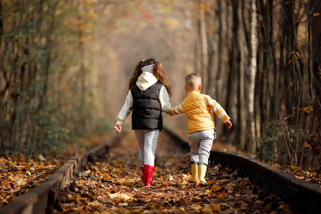 秋のロマンチックな場所で秋の時間を愛のトンネルを笑顔の鉄道の上を歩くかわいい男の子と女の子