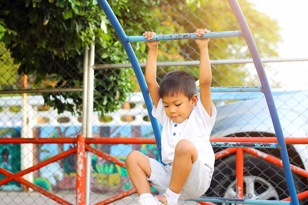 Cute boy hanging from outdoor play equipment at playground