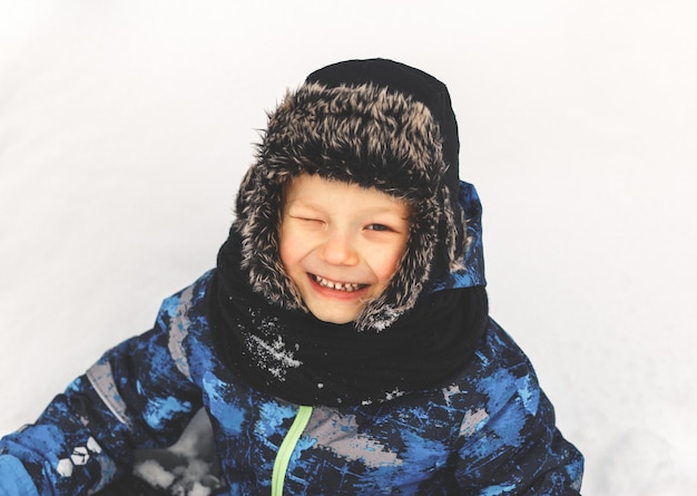 A cute boy in a hat laughs in the winter in the street. Winter portrait