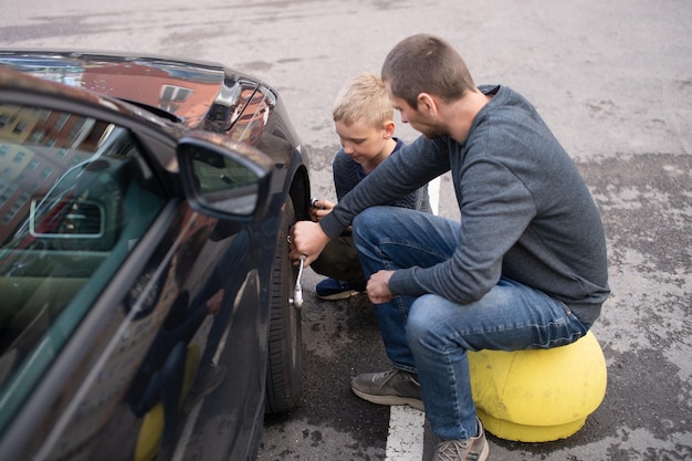 Cute boy helps Dad fix the car Unscrew the wheel