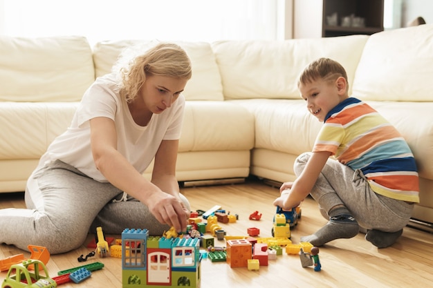 Cute boy and his happy mother playing together at home