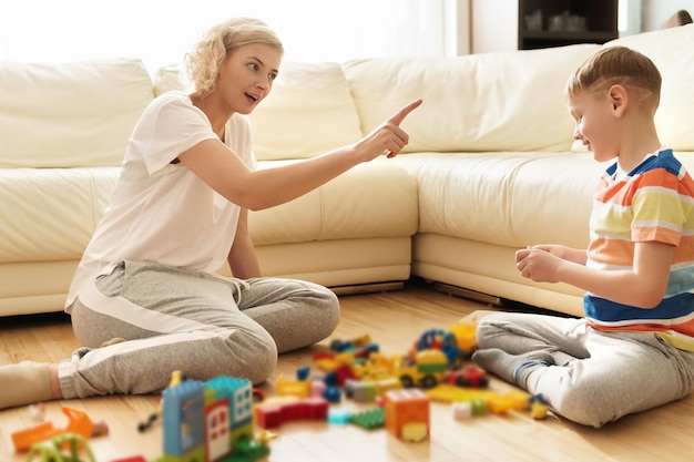 Cute boy and his happy mother playing together at home