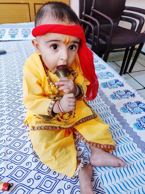 Cute boy holding bell while sitting on bed at home