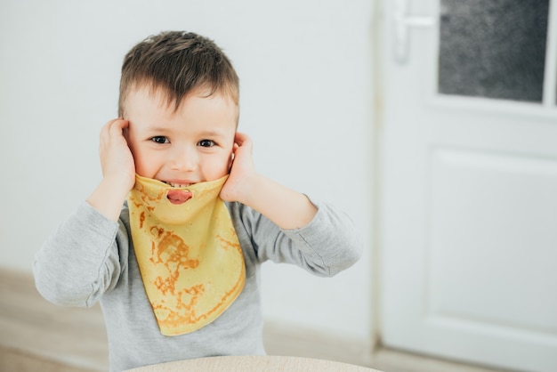 Cute boy holding a pancake to his mouth playing fun cute