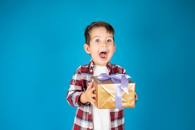귀여운 소년은 선물 상자를 들고 있고 매우 놀란 휴일 및 생일 개념 고품질 사진