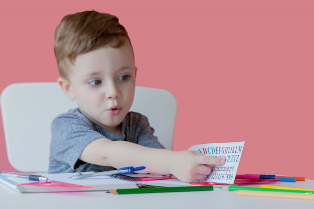 Cute boy at home writing with colorful pencil