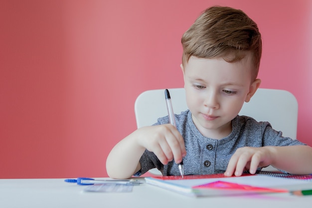 Cute boy at home writing with colorful pencil