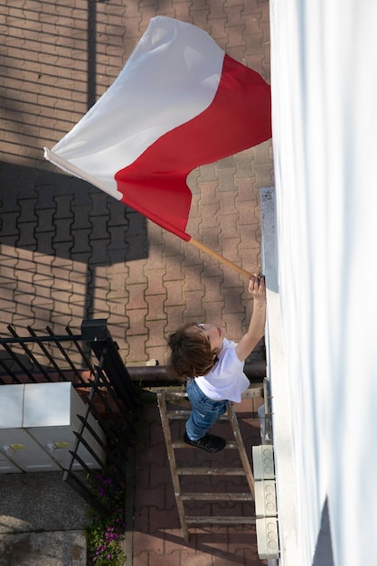 The cute boy is hanging a Polish flag Polish National Day of the Third of May